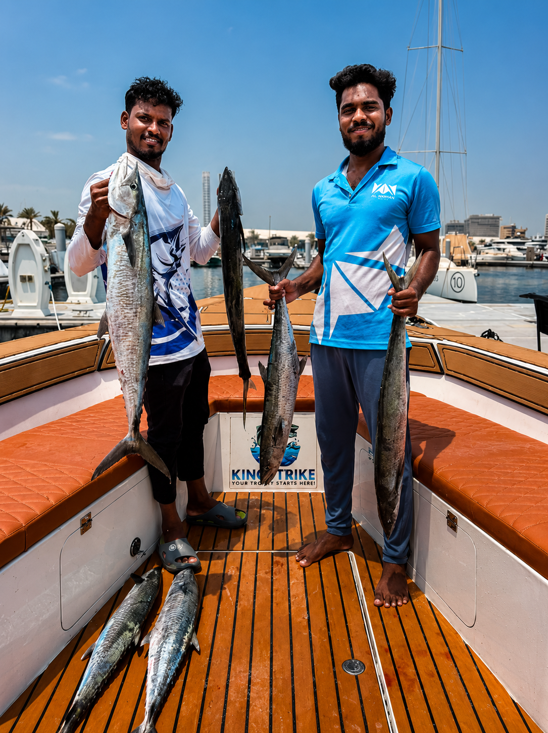 Two KingStrike crew members holding up kingfish on the bow at Port Rashid